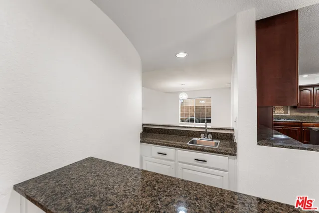 a kitchen with granite countertop white cabinets and white appliances