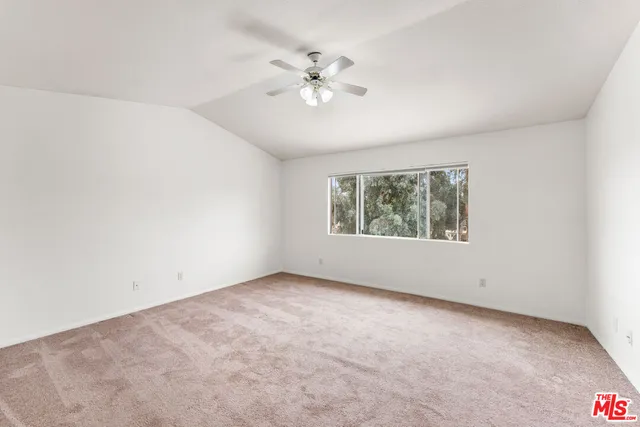 an empty room with a window and a ceiling fan