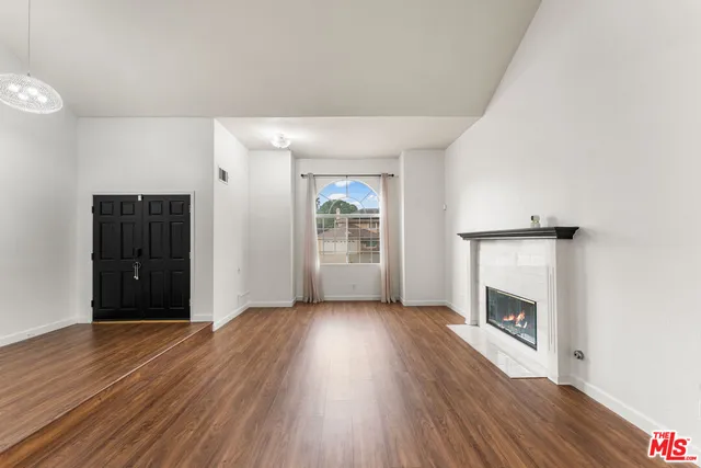 a view of an empty room with wooden floor fireplace and a window