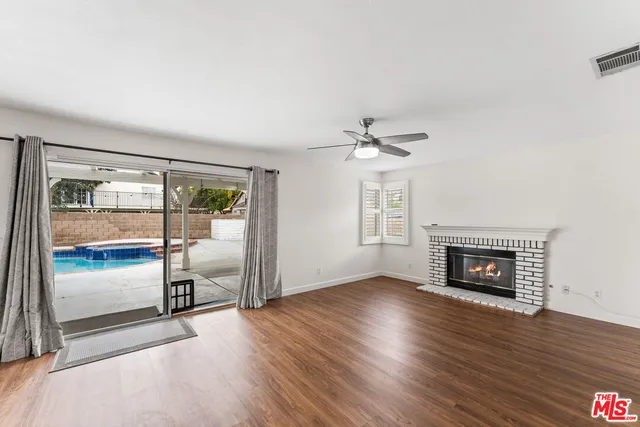 an empty room with wooden floor fireplace and windows