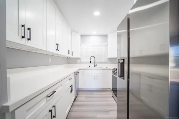 a kitchen with stainless steel appliances granite countertop a sink a stove and microwave with wooden floor