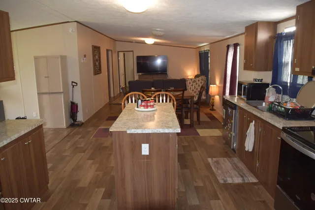 a view of a kitchen with kitchen island wooden floors granite counter tops and white appliances