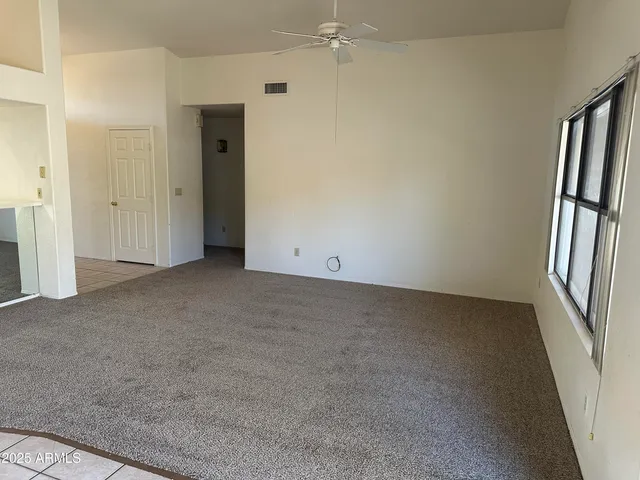 an empty room with a window and a fan