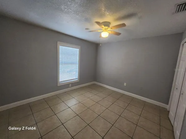 an empty room with windows and chandelier fan