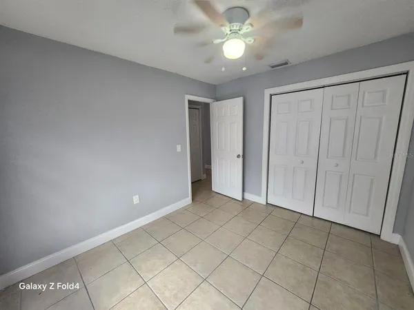 a view of an empty room and chandelier fan