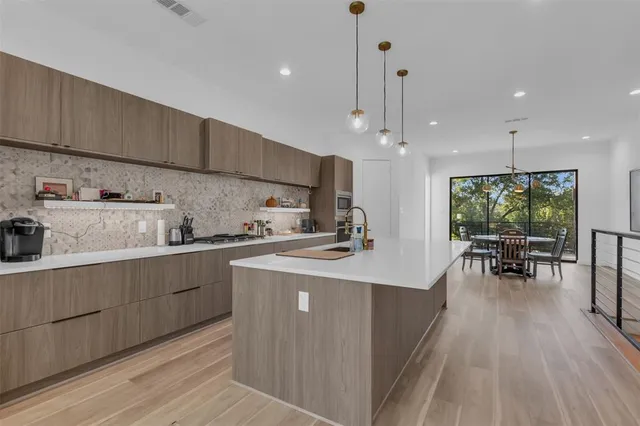a kitchen with stainless steel appliances kitchen island granite countertop a table chairs in it and wooden floors