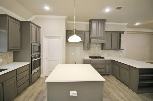 a large kitchen with a large counter top stainless steel appliances and cabinets