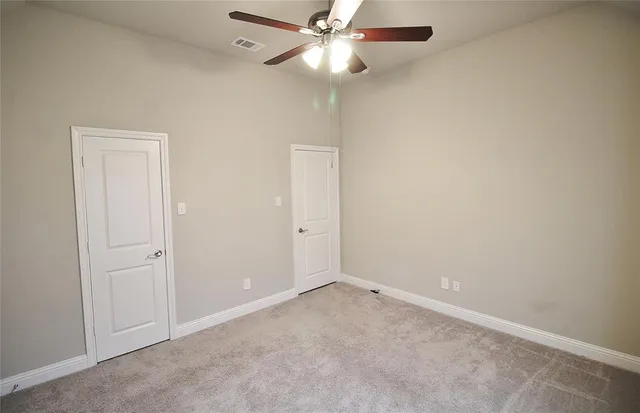 an empty room with a fan & a ceiling fan
