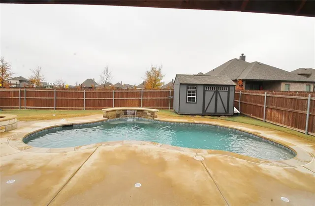 a view of a backyard with swimming pool and brick wall