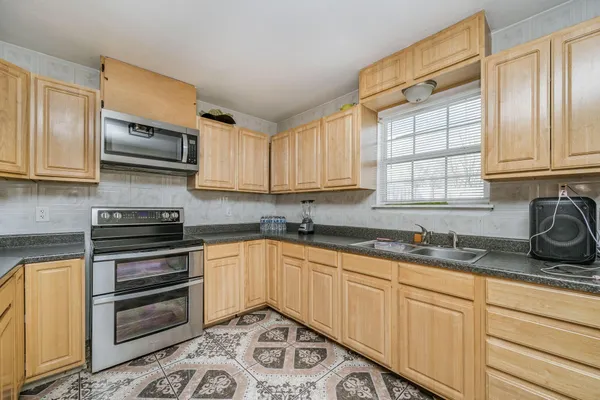 a kitchen with granite countertop a sink a stove and cabinets