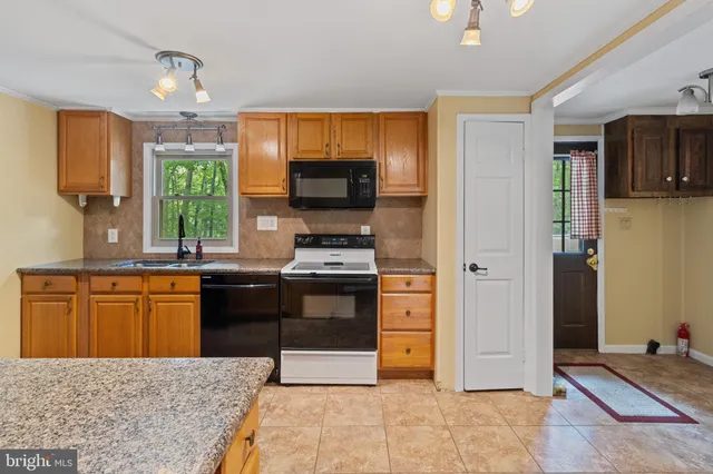 a kitchen with stainless steel appliances granite countertop a stove top oven a sink dishwasher a dining table and chairs with wooden floor