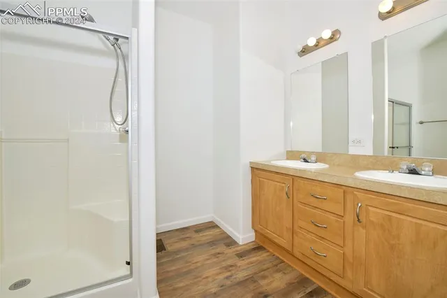 a bathroom with a granite countertop sink two mirror and a shower