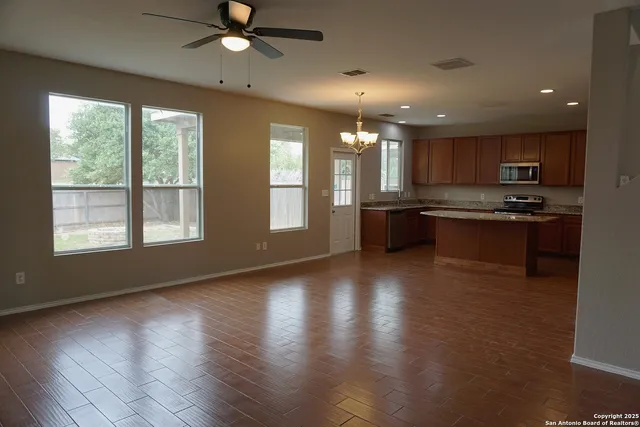 a kitchen with stainless steel appliances granite countertop a stove a sink a refrigerator and a dining table with wooden floor