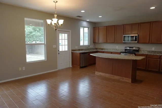 a kitchen with stainless steel appliances granite countertop wooden cabinets a stove a sink and a window