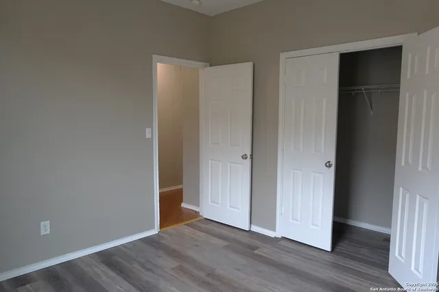 an empty room with wooden floor & closet area