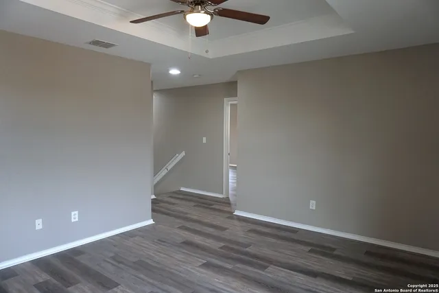 an empty room with wooden floor and fan