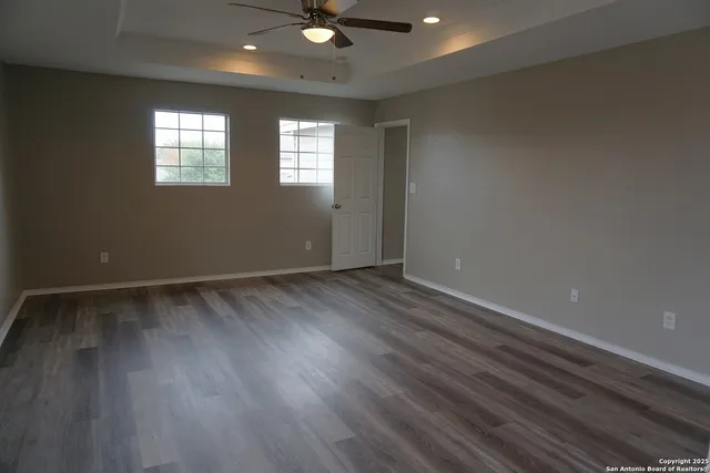 an empty room with wooden floor and windows