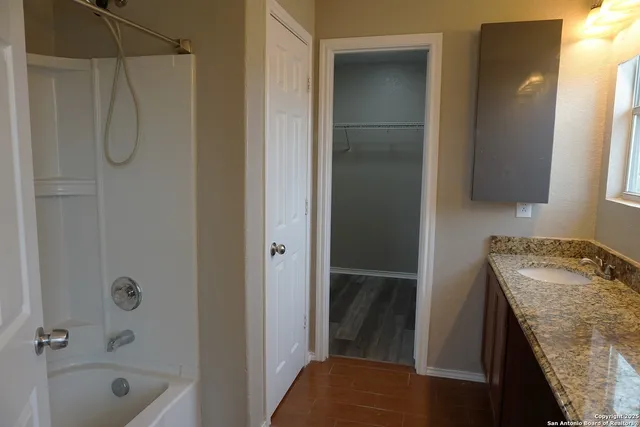 a bathroom with a granite countertop sink a mirror and shower