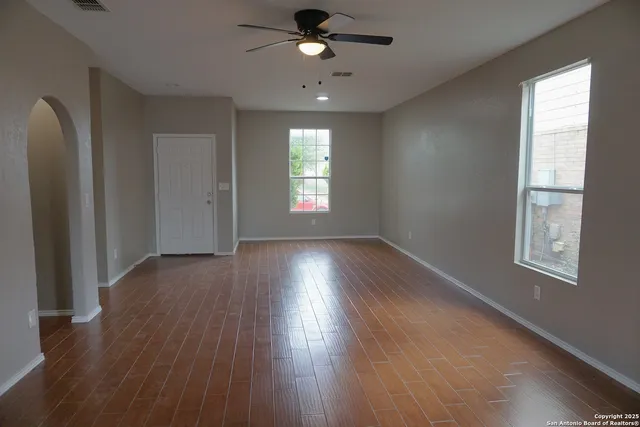 a view of empty room with wooden floor and fan