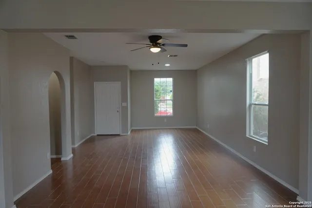 a view of an empty room with wooden floor and a window