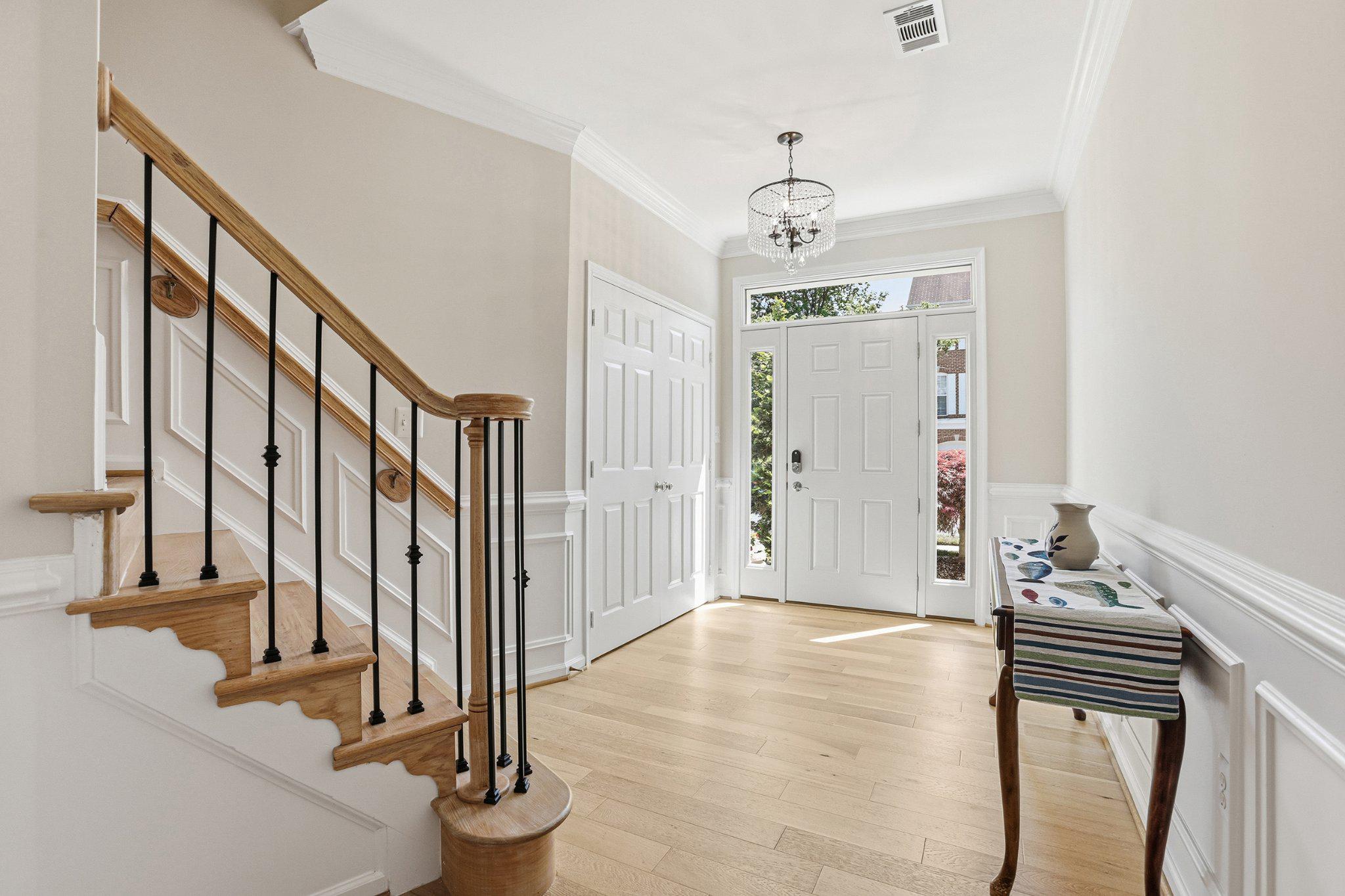 Foyer with crystal chandelier, hardwood staircase