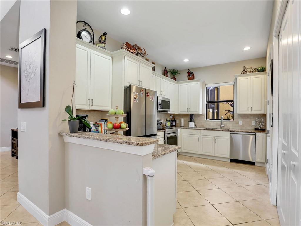1242 Kendari Terrace Naples, FL 34113 - Photo 13 of 44 a kitchen with white cabinets and refrigerator