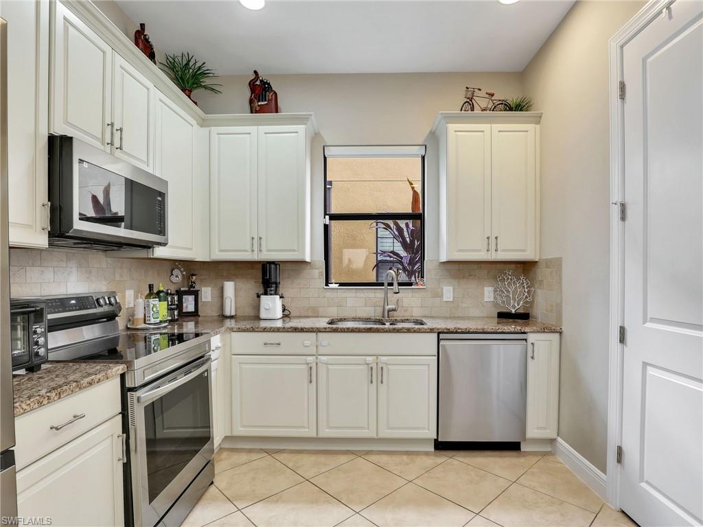 1242 Kendari Terrace Naples, FL 34113 - Photo 14 of 44 a kitchen with cabinets stainless steel appliances and a sink