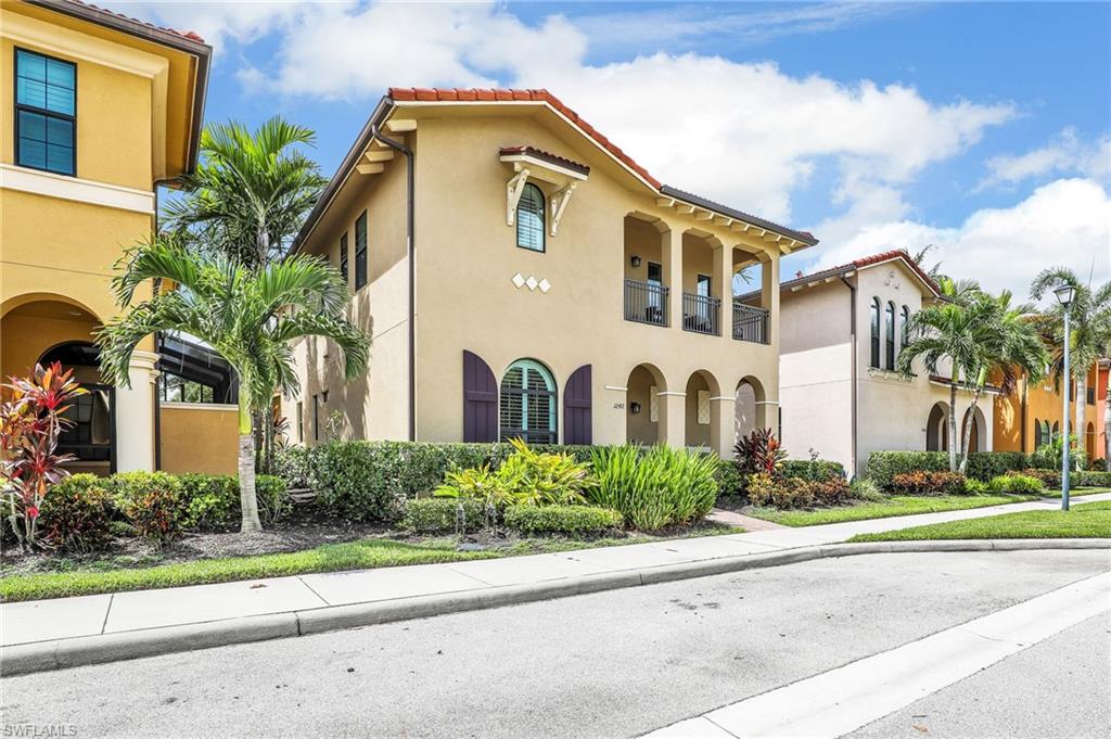 1242 Kendari Terrace Naples, FL 34113 - Photo 29 of 44 a front view of yellow house with a yard and potted plants
