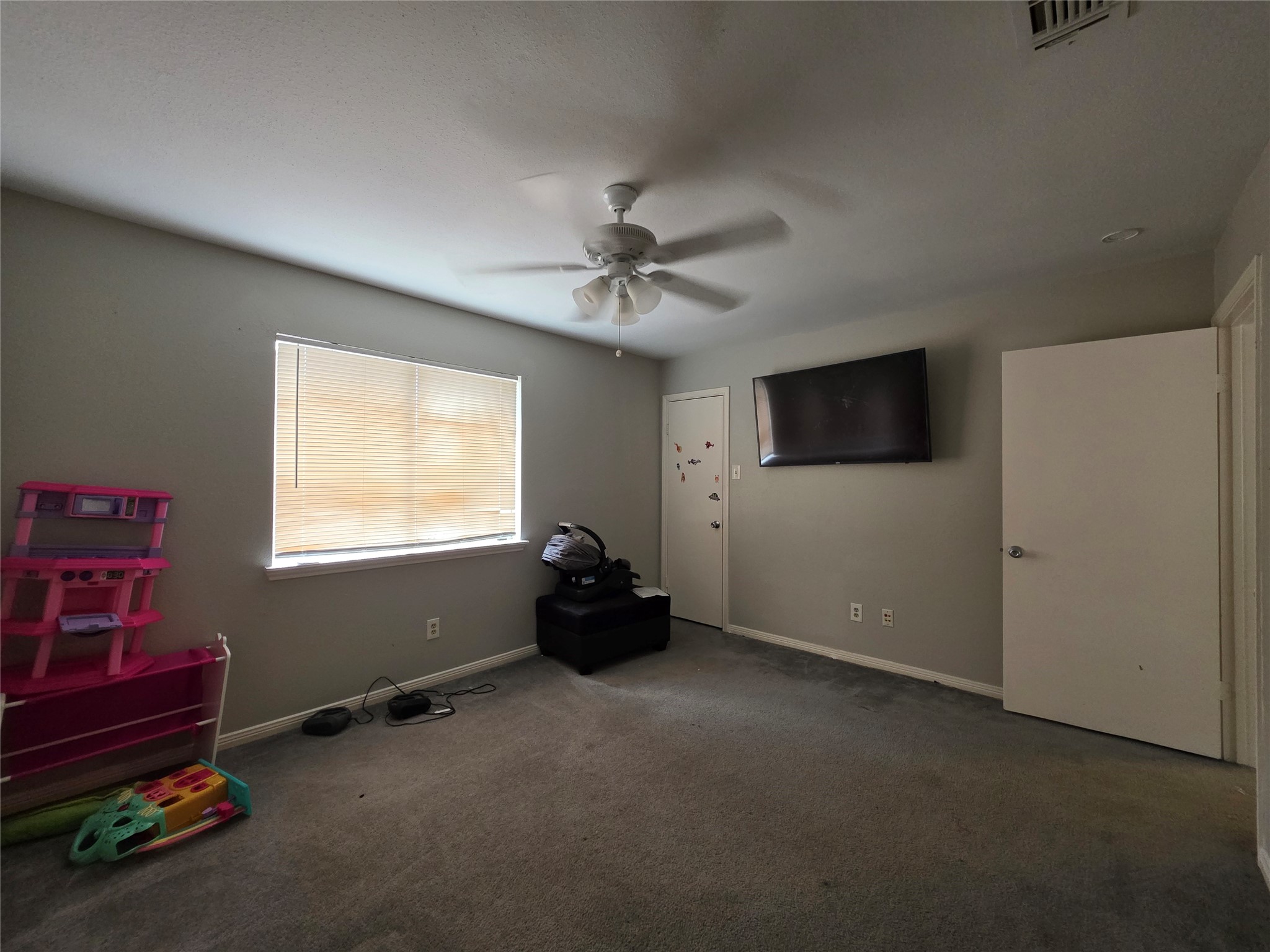 15615 Fern Ridge Drive Houston, TX 77084 - Photo 25 of 31 Cozy room with neutral walls and a ceiling fan, featuring a large window for natural light and ample space for play or relaxation.