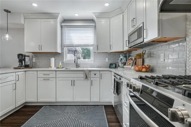 a kitchen with stainless steel appliances granite countertop a stove a sink and a microwave