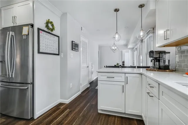 a kitchen with stainless steel appliances granite countertop a refrigerator a sink and white cabinets