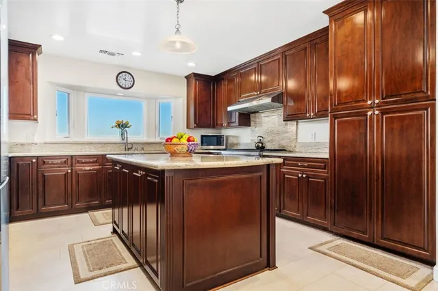 a kitchen with stainless steel appliances granite countertop wooden cabinets a refrigerator a sink and a stove