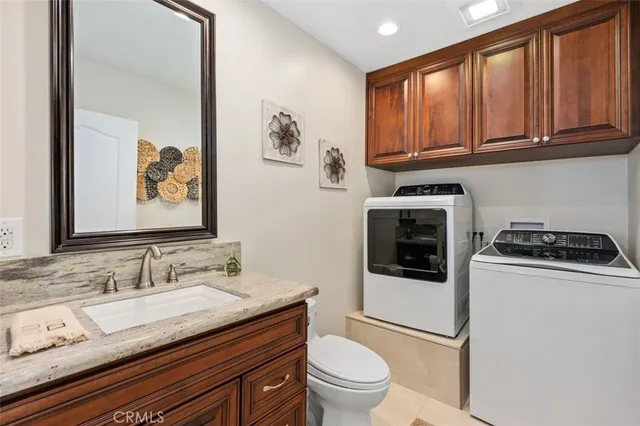 a bathroom with a granite countertop sink a toilet and a mirror