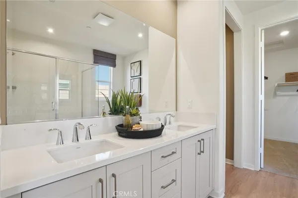 a bathroom with double vanity sinks a large mirror and a shower