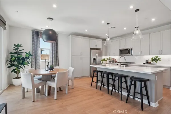 a kitchen with stainless steel appliances kitchen island granite countertop a dining table chairs and white cabinets