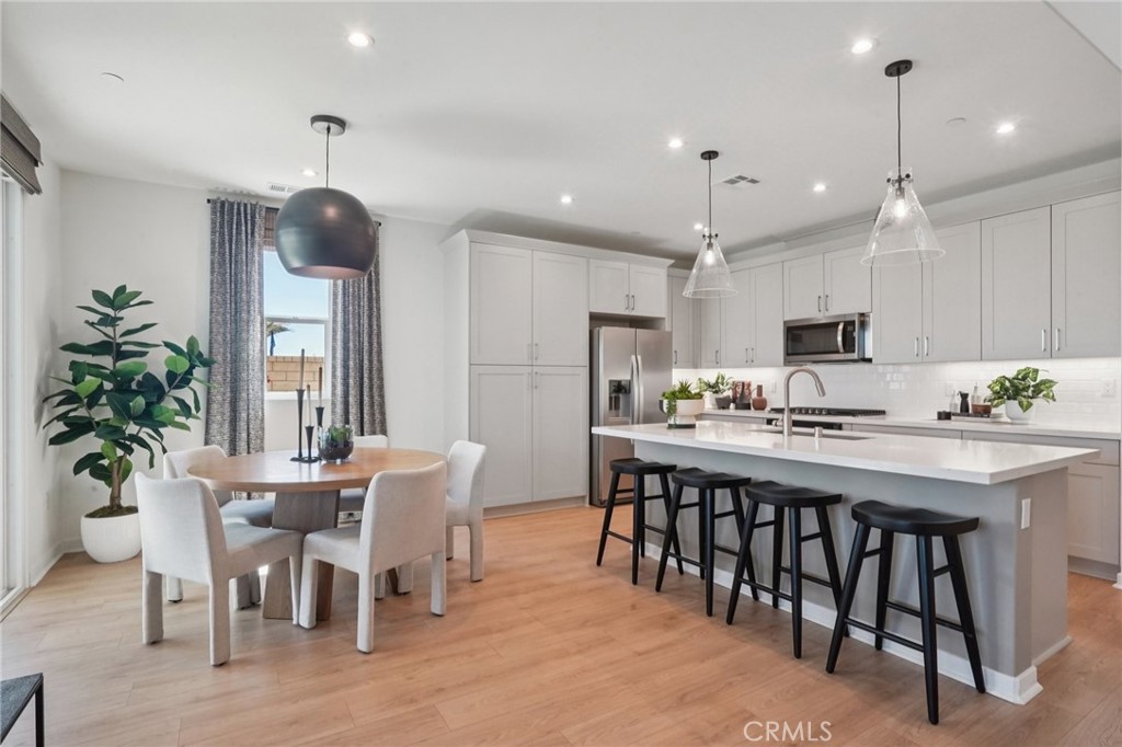 73634 Raphael Drive Palm Desert, CA 92211 - Photo 5 of 24 a kitchen with stainless steel appliances kitchen island granite countertop a dining table chairs and white cabinets