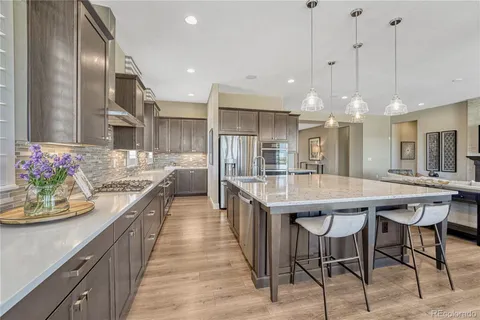 a kitchen with stainless steel appliances kitchen island granite countertop a table chairs in it and wooden floors