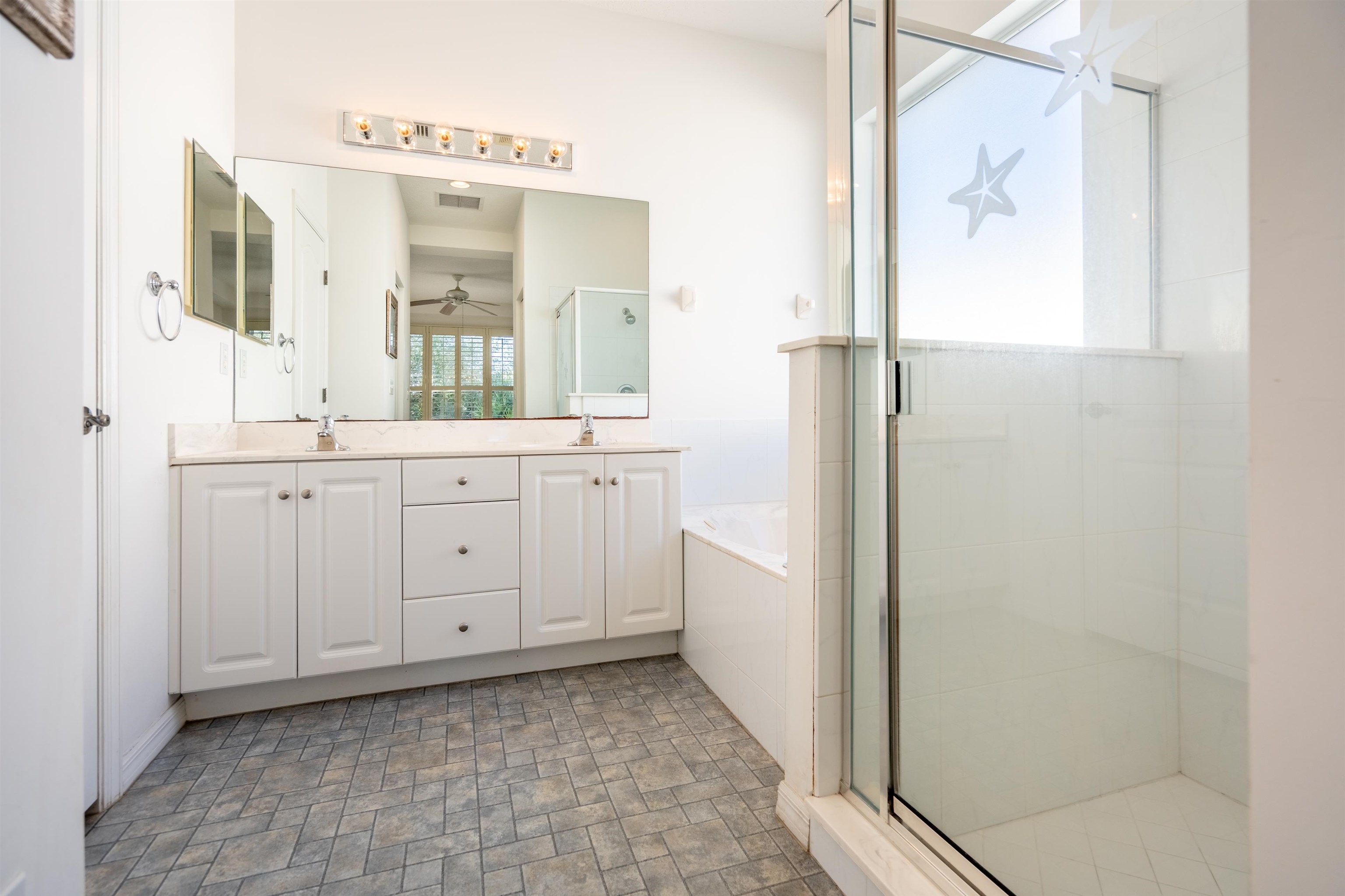 660 Casa Fuerta Lane St. Augustine, FL 32080 - Photo 1 of 52 Bathroom with a shower stall, double vanity, a garden tub, stone finish flooring, and ceiling fan