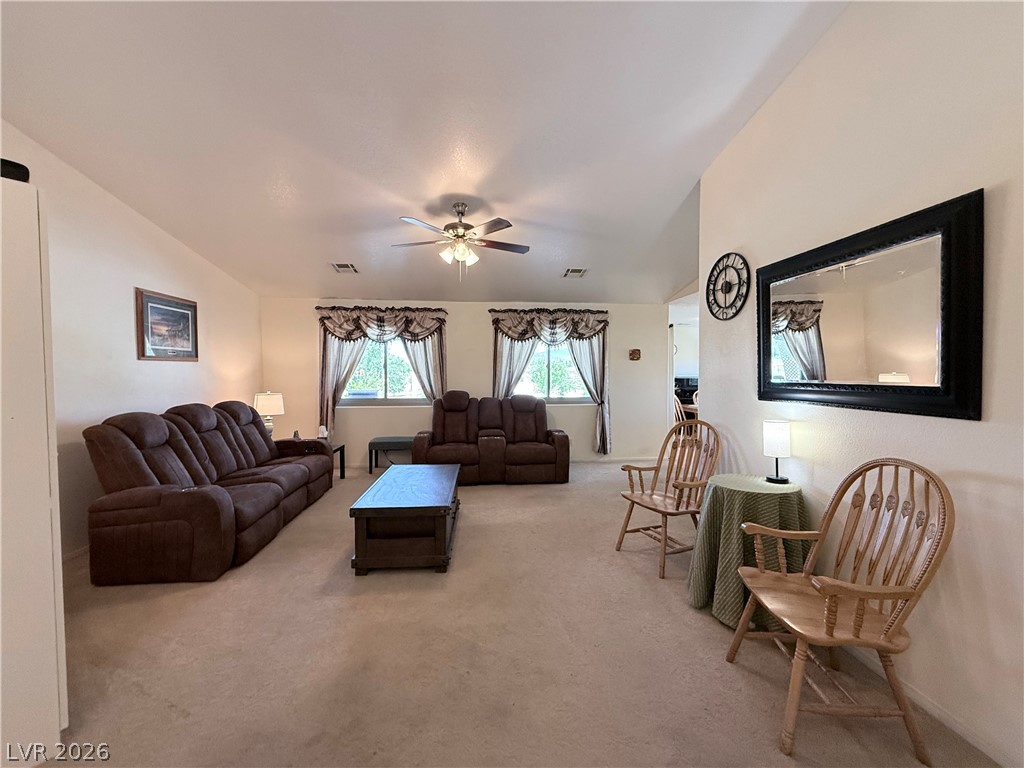 1220 East Gamebird Road Pahrump, NV 89048 - Photo 4 of 49 A comfortable living area features ample natural light from multiple windows and a ceiling fan.