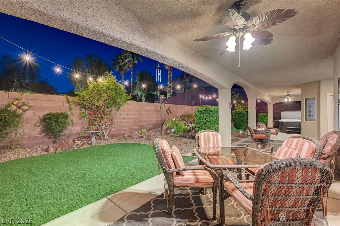 1604 Cattle Ranch Place Henderson, NV 89002 - Photo 5 of 99 An inviting covered patio with a ceiling fan overlooks a landscaped private yard under a starry night.