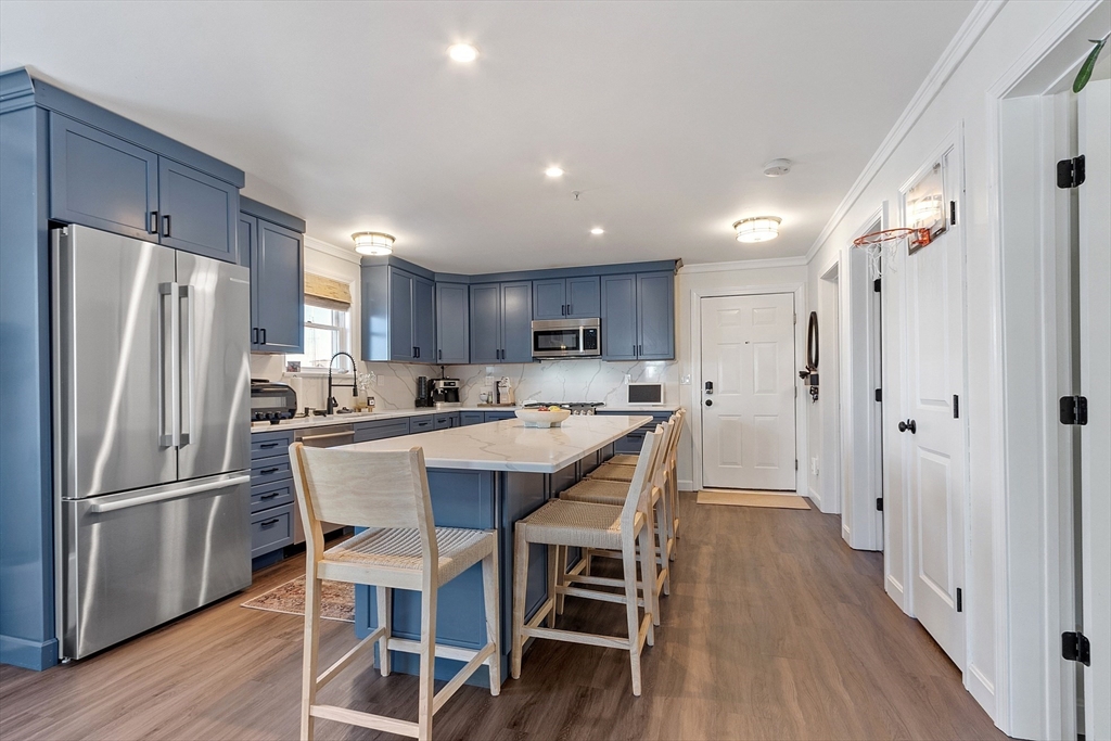 20 Cable Avenue, Unit 5 Salisbury, MA 01952 - Photo 8 of 23 a kitchen with stainless steel appliances a refrigerator a sink dishwasher a dining table and chairs with wooden floor