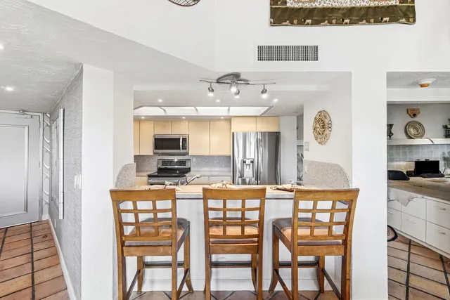 a kitchen with stainless steel appliances kitchen island granite countertop a refrigerator and microwave