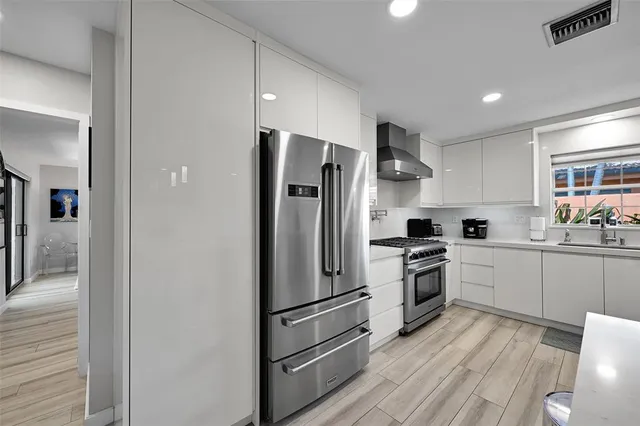 a kitchen with cabinets stainless steel appliances and wooden floor