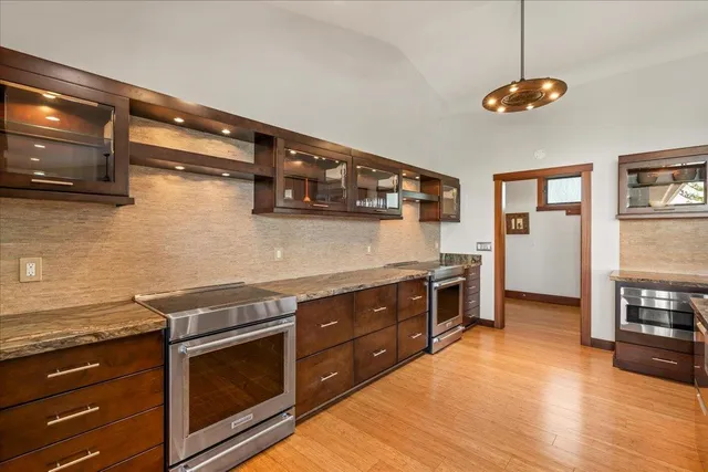 a kitchen with stainless steel appliances granite countertop a stove top oven a dining table and chairs with wooden floor