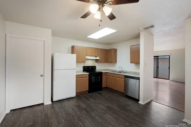 a kitchen with a refrigerator a stove top oven a sink and dishwasher with wooden floor