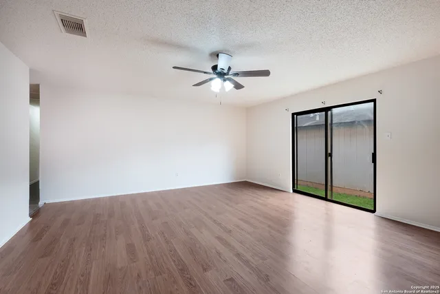 an empty room with wooden floor and a ceiling fan