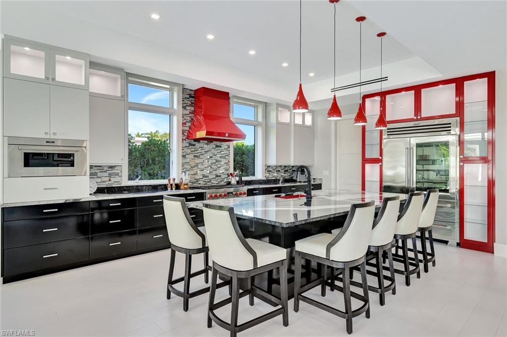 739 5th Avenue North Naples, FL 34102 - Photo 11 of 35 a kitchen with stainless steel appliances granite countertop a stove a sink dishwasher a dining table and chairs with wooden floor