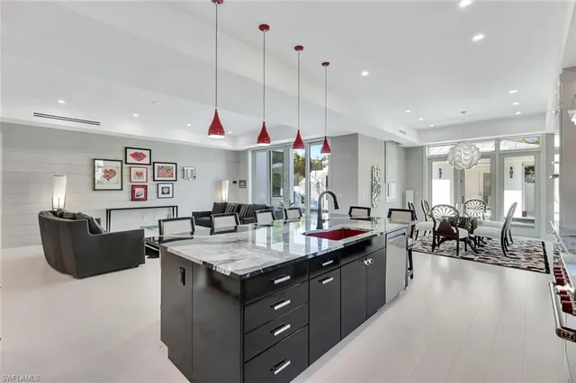 a kitchen island with granite countertop a sink a counter top space and living room view