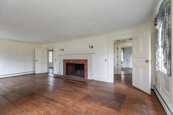 an empty room with wooden floor fireplace and windows