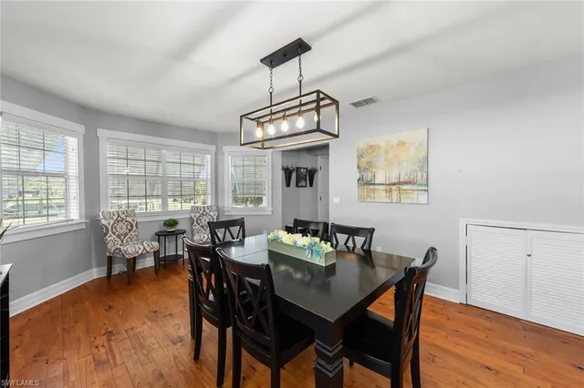 a dining room with wooden floor a chandelier a wooden table and chairs